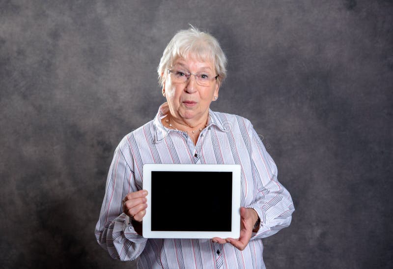 Donna anziana pelosa grigia che per mezzo del pc della compressa fotografia stock libera da diritti