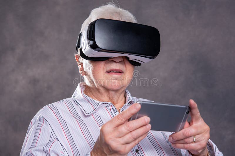 Donna anziana pelosa grigia che usando i vetri di realtà virtuale fotografia stock libera da diritti