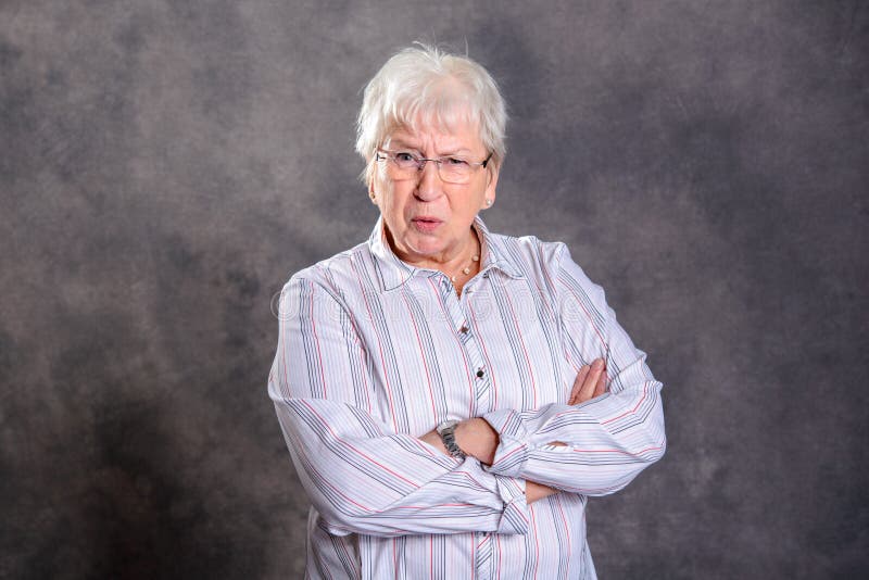 Donna anziana pelosa grigia con le armi attraversate che sembrano arrabbiate fotografia stock libera da diritti