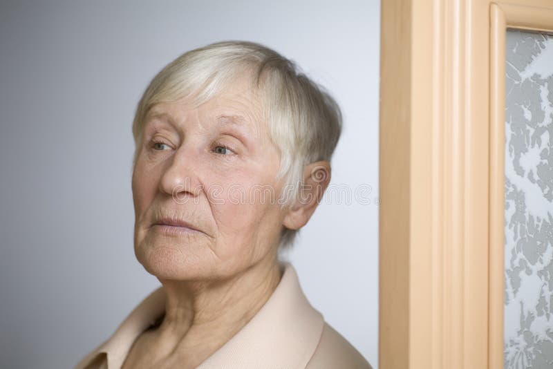 Donna anziana premurosa che distoglie lo sguardo dalla porta fotografia stock Donna anziana premurosa che distoglie lo sguardo dalla porta fotografia stock