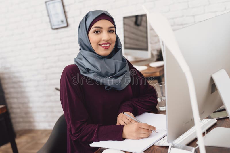 Donna araba che lavora nell'ufficio La lavoratrice sta prendendo le note alla tavola fotografia stock Donna araba che lavora nell'ufficio La lavoratrice sta prendendo le note alla tavola fotografia stock