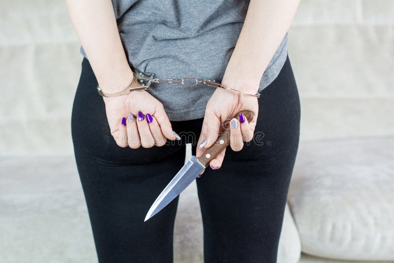 Donna arrestata con un coltello Mani ammanettate sul retro fotografie stock Donna arrestata con un coltello Mani ammanettate sul retro fotografie stock