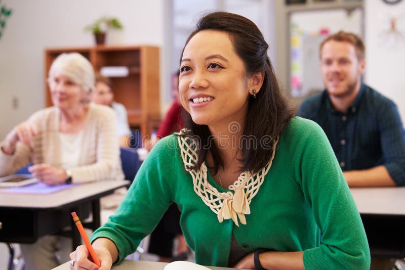 Donna asiatica che esamina il bordo in una classe di corsi per adulti fotografia stock Donna asiatica che esamina il bordo in una classe di corsi per adulti fotografia stock