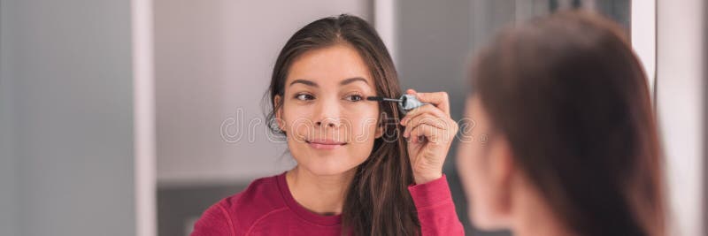 Donna asiatica che si prepara per il trucco del mascara mentre si prepara il banner panoramico del bagno di casa fotografia stock
