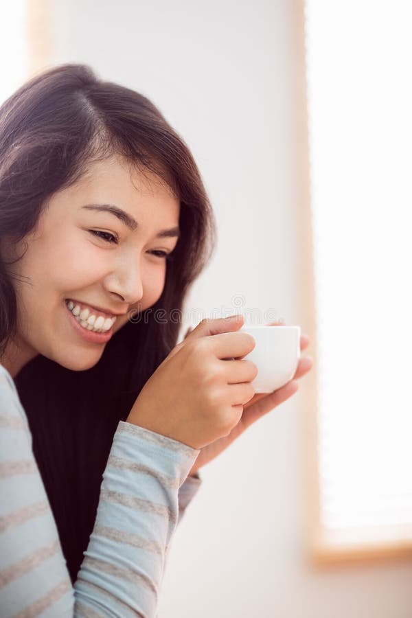Donna asiatica che si rilassa sullo strato con caffè immagini stock libere da diritti Donna asiatica che si rilassa sullo strato con caffè immagini stock libere da diritti