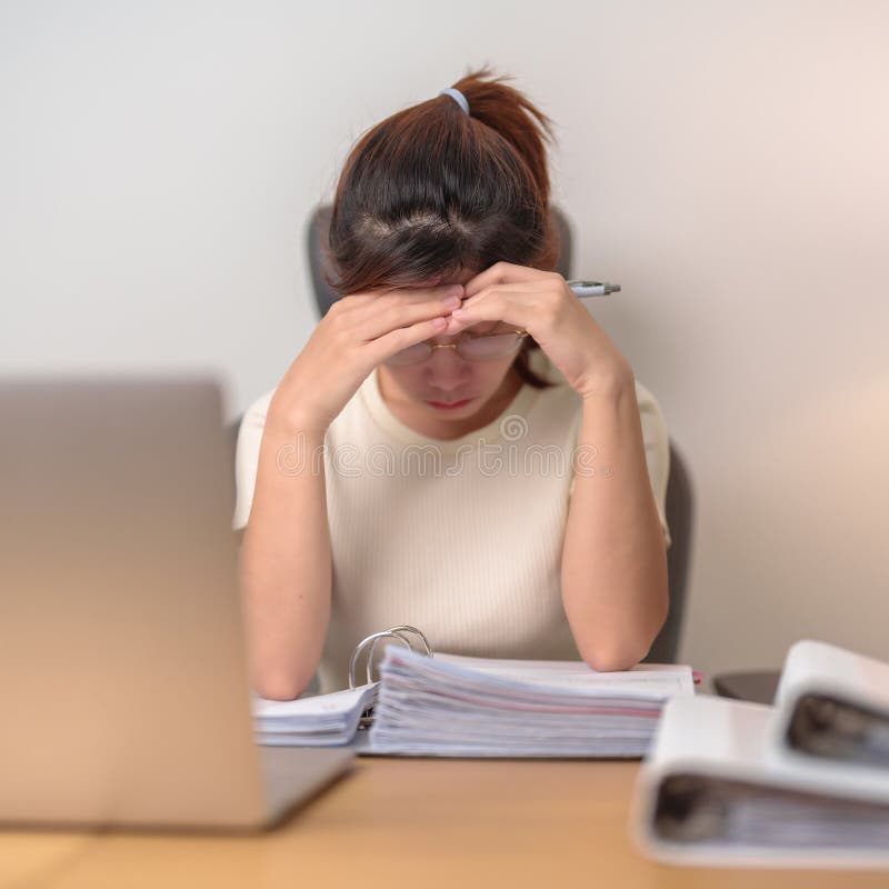 Donna asiatica stressata che usa un computer portatile donna d'affari stanca che lavora con mal di testa e assonnata all'ufficio e immagine stock