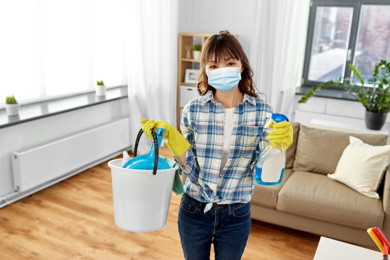 Donna asiatica in una casa di pulizia con maschera protettiva