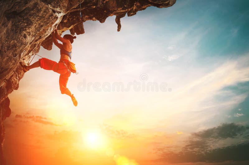 Donna atletica che scala sulla roccia sporgentesi della scogliera con il fondo del cielo di tramonto fotografia stock libera da diritti Donna atletica che scala sulla roccia sporgentesi della scogliera con il fondo del cielo di tramonto fotografia stock libera da diritti