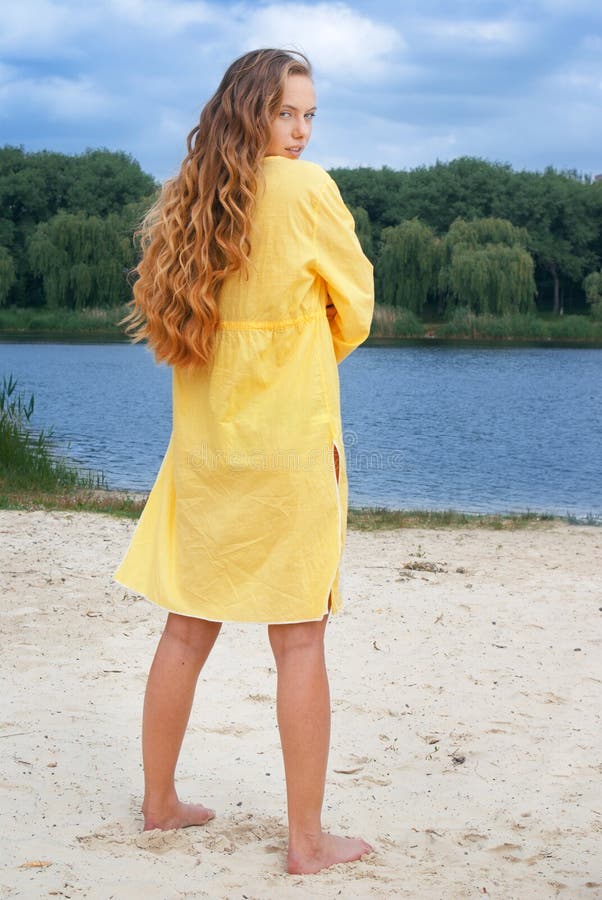 Donna attraente in attrezzatura gialla sulla spiaggia del fiume fotografie stock Donna attraente in attrezzatura gialla sulla spiaggia del fiume fotografie stock