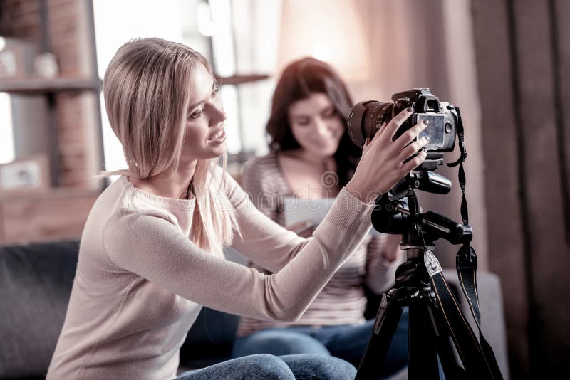 Donna bionda allegra che ripara la sua videocamera portatile fotografie stock Donna bionda allegra che ripara la sua videocamera portatile fotografie stock