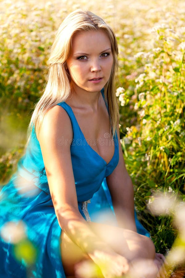 Donna bionda che porta vestito blu su un campo fotografie stock