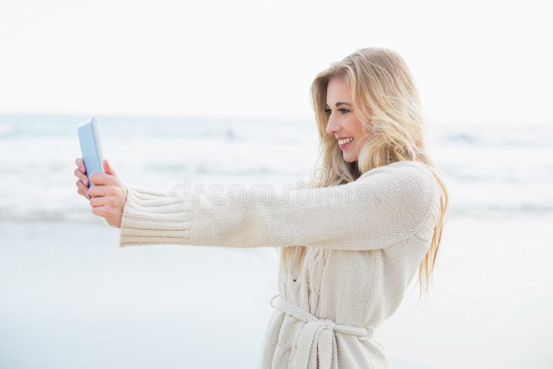 Donna bionda divertente nel cardigan della lana che prende un'immagine se stessa con un pc della compressa fotografie stock libere da diritti Donna bionda divertente nel cardigan della lana che prende un'immagine se stessa con un pc della compressa fotografie stock libere da diritti
