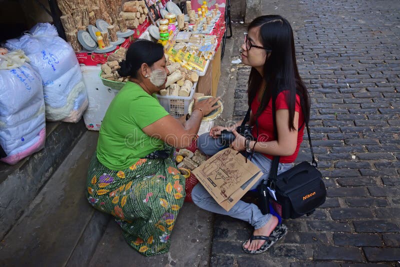 Donna birmana che contribuisce ad applicare la pasta appena fatta di Thanaka ad una giovane ragazza turistica straniera fotografia stock libera da diritti