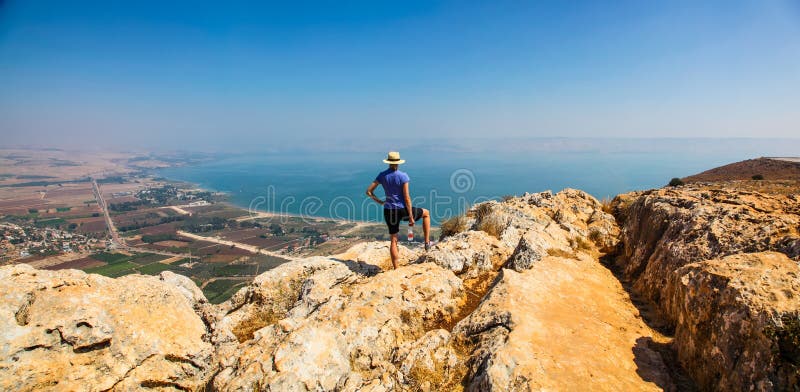 Donna in cappello che gode della vista panoramica del mare della Galilea fotografia stock libera da diritti Donna in cappello che gode della vista panoramica del mare della Galilea fotografia stock libera da diritti