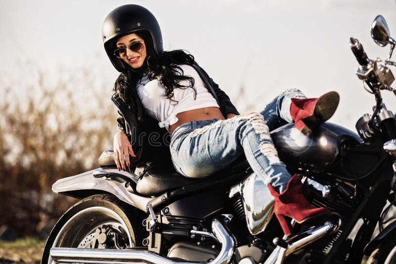 Donna castana del bello motociclo con un motociclo classico c fotografie stock libere da diritti Donna castana del bello motociclo con un motociclo classico c fotografie stock libere da diritti