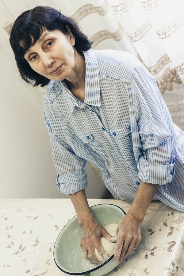 Donna castana di mezza età che impasta producendo pasta per gli gnocchi in ciotola blu immagine stock libera da diritti Donna castana di mezza età che impasta producendo pasta per gli gnocchi in ciotola blu immagine stock libera da diritti