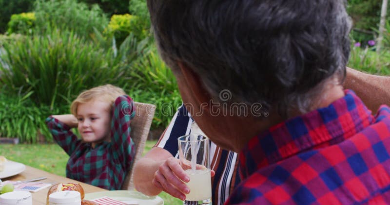 Donna caucasica anziana che serve una limonata di moglie a pranzo di festa in giardino