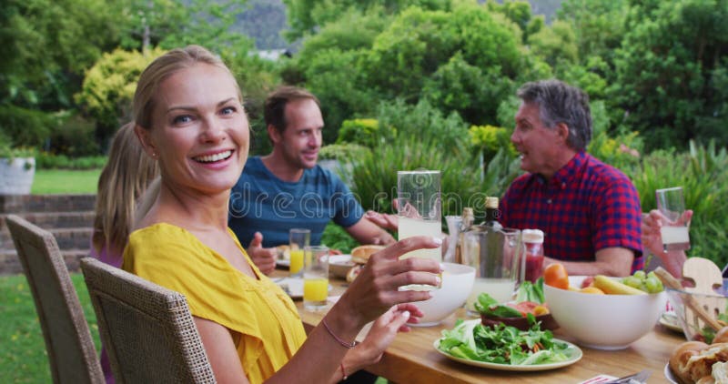 Donna caucasica che prepara un brindisi girando e sorridendo durante la festa della famiglia in giardino