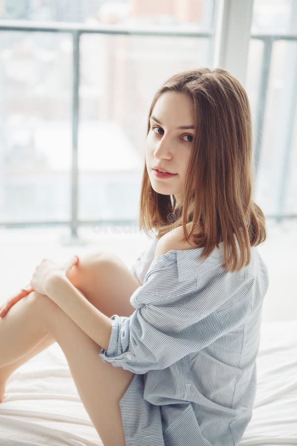 Donna caucasica con capelli biondi rossi lunghi in pigiama blu della camicia che si siede a letto fotografie stock libere da diritti Donna caucasica con capelli biondi rossi lunghi in pigiama blu della camicia che si siede a letto fotografie stock libere da diritti