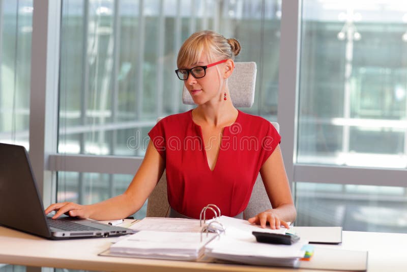 Donna caucasica di affari in occhiali che lavorano al computer portatile immagine stock Donna caucasica di affari in occhiali che lavorano al computer portatile immagine stock