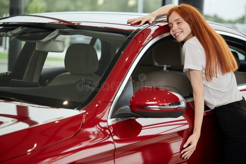 Donna caucasica felice che abbraccia la sua nuova automobile alla gestione commerciale automatica immagini stock libere da diritti Donna caucasica felice che abbraccia la sua nuova automobile alla gestione commerciale automatica immagini stock libere da diritti