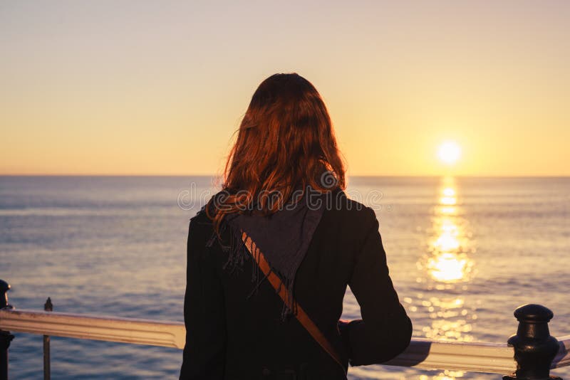 Donna che ammira il mare al tramonto immagini stock libere da diritti Donna che ammira il mare al tramonto immagini stock libere da diritti
