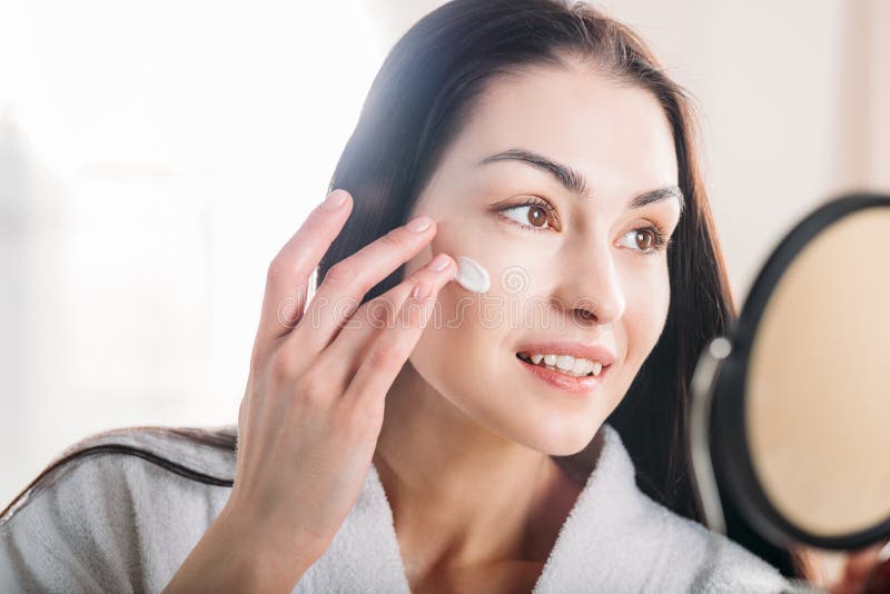 Donna che applica la crema di fronte fotografia stock libera da diritti Donna che applica la crema di fronte fotografia stock libera da diritti