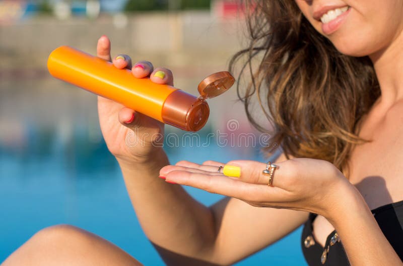 Donna che applica la lozione del sole dallo stagno immagini stock libere da diritti Donna che applica la lozione del sole dallo stagno immagini stock libere da diritti