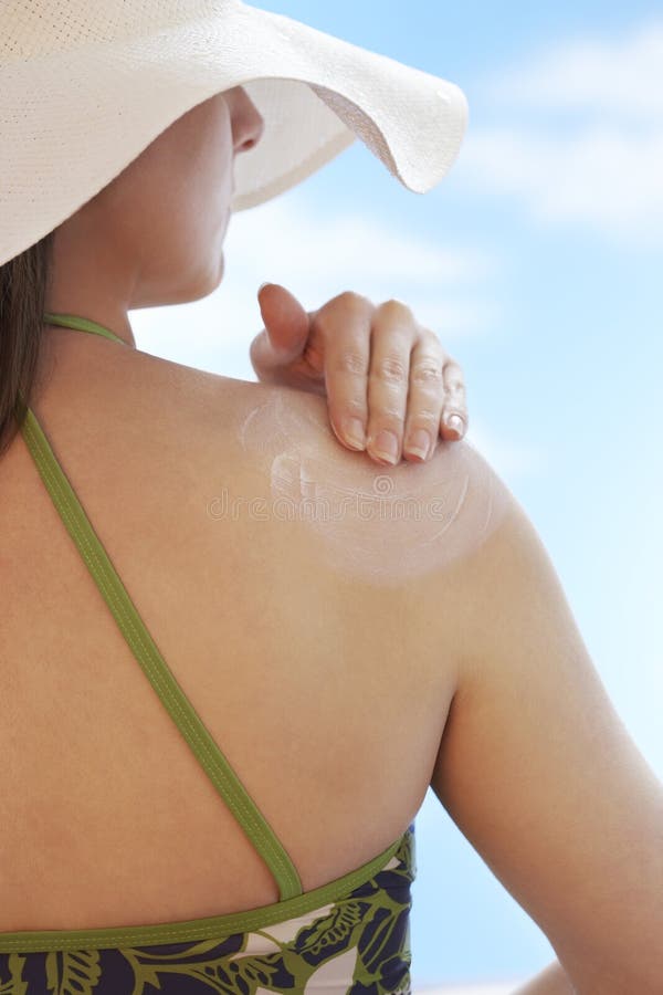 Donna che applica protezione solare alla spalla immagini stock Donna che applica protezione solare alla spalla immagini stock
