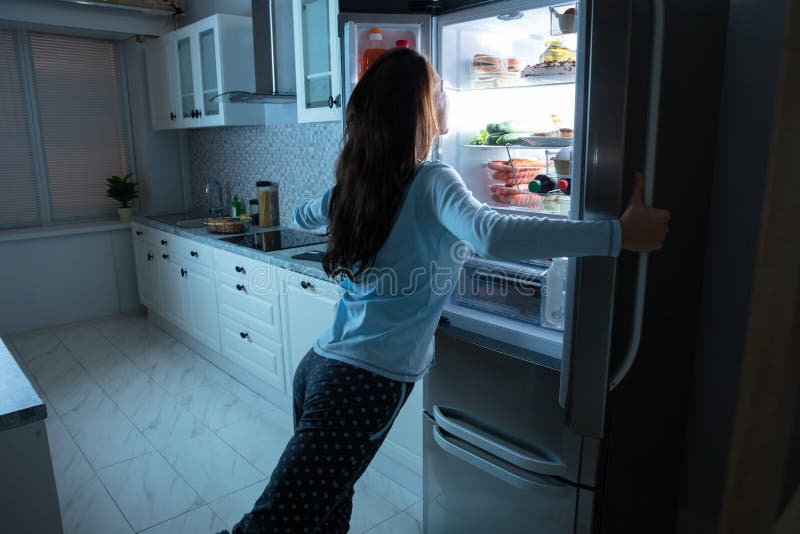 Donna che apre la porta del frigorifero