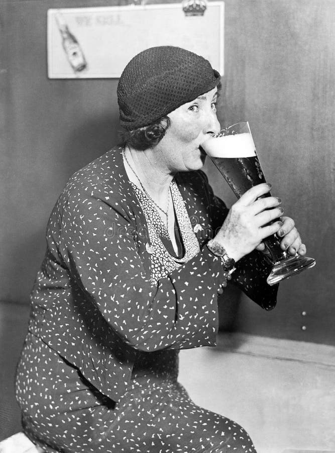 Donna che beve da un grande vetro di birra (tutte le persone rappresentate non sono vivente più lungo e nessuna proprietà esiste