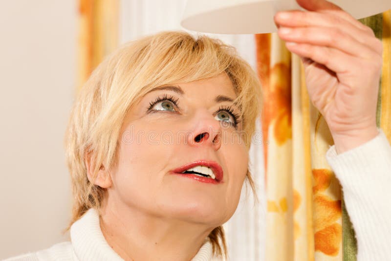 Donna che cambia una lampadina fotografie stock libere da diritti Donna che cambia una lampadina fotografie stock libere da diritti