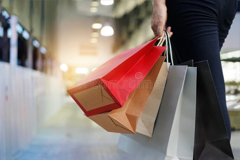 Donna che cammina con i sacchetti della spesa sul fondo del centro commerciale