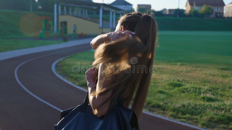 Donna che cammina con la borsa allo stadio per allenarsi.