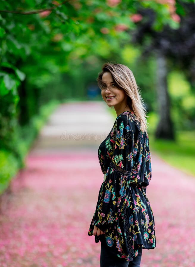 Donna che cammina gi? al vicolo con gli alberi del fiore immagine stock Donna che cammina gi? al vicolo con gli alberi del fiore immagine stock