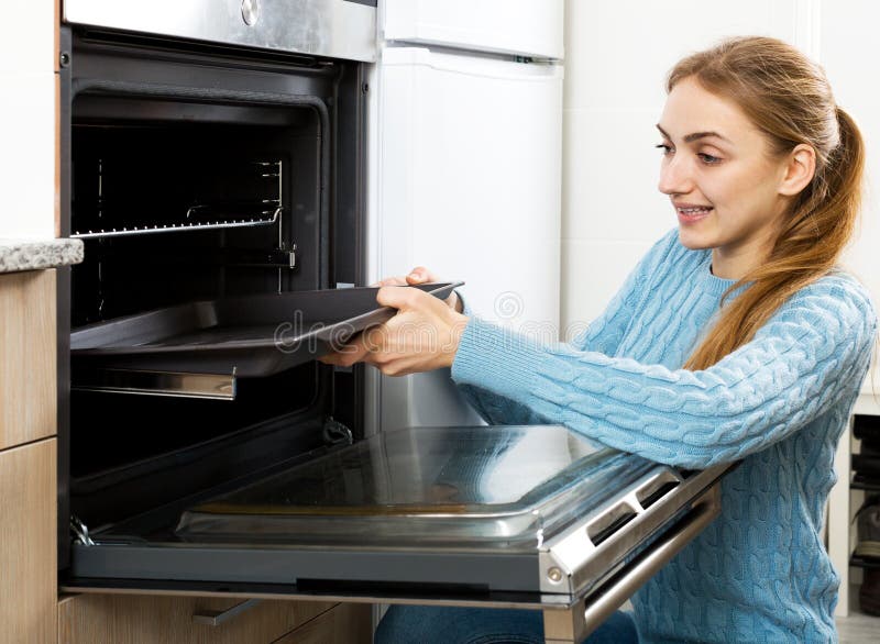 Donna che dispone il vassoio di torrefazione in forno della cucina fotografia stock Donna che dispone il vassoio di torrefazione in forno della cucina fotografia stock