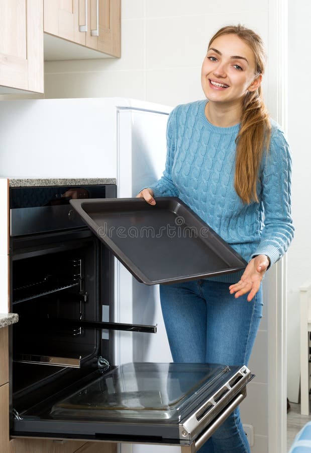 Donna che dispone il vassoio di torrefazione in forno della cucina fotografia stock Donna che dispone il vassoio di torrefazione in forno della cucina fotografia stock