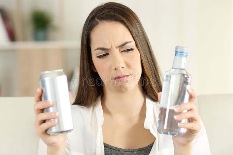 Donna che dubita fra la bevanda della soda e l'acqua fotografia stock libera da diritti Donna che dubita fra la bevanda della soda e l'acqua fotografia stock libera da diritti