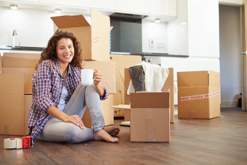 Donna che entra nella nuova casa e che disimballa le scatole fotografie stock libere da diritti Donna che entra nella nuova casa e che disimballa le scatole fotografie stock libere da diritti