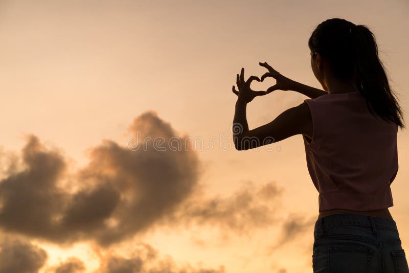 Donna che fa simbolo del cuore con le sue mani al tramonto fotografia stock libera da diritti Donna che fa simbolo del cuore con le sue mani al tramonto fotografia stock libera da diritti