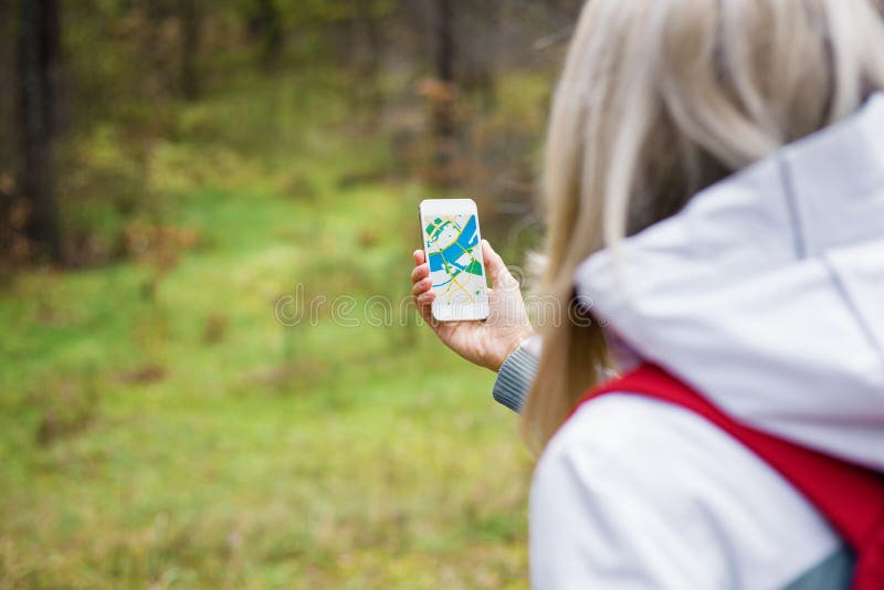 Donna che geocaching nella foresta e che usando mappa app sullo smartphone