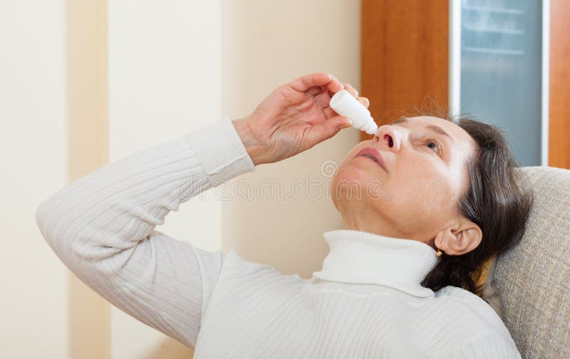 Mature woman dripping nasal drops. Mature woman dripping nasal drops