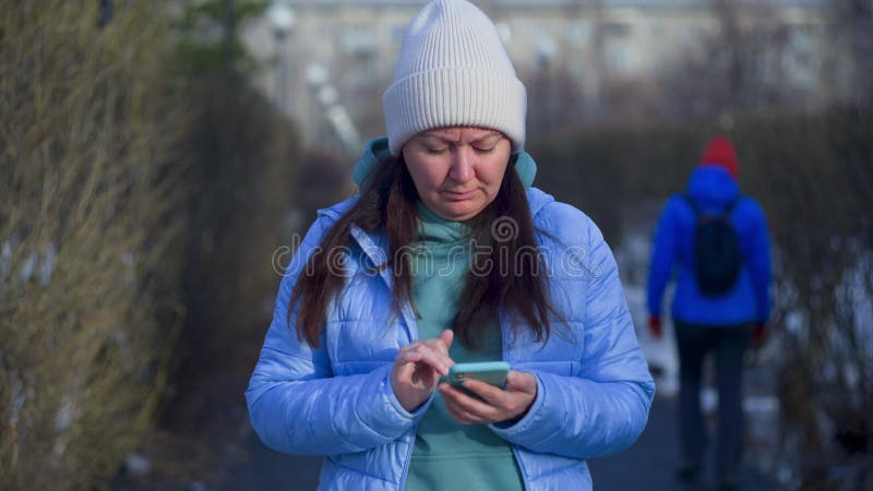 Donna che guarda gli smartphone navigare su internet mentre sta a Park.