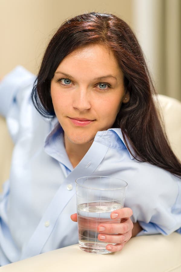 Donna che guarda macchina fotografica che tiene bicchiere d'acqua immagine stock libera da diritti Donna che guarda macchina fotografica che tiene bicchiere d'acqua immagine stock libera da diritti
