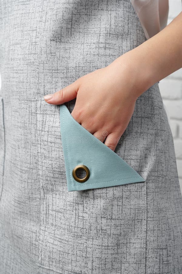 Donna che indossa un grembiule grigio con una camicia bianca davanti a un muro di mattoni bianchi fotografia stock libera da diritti