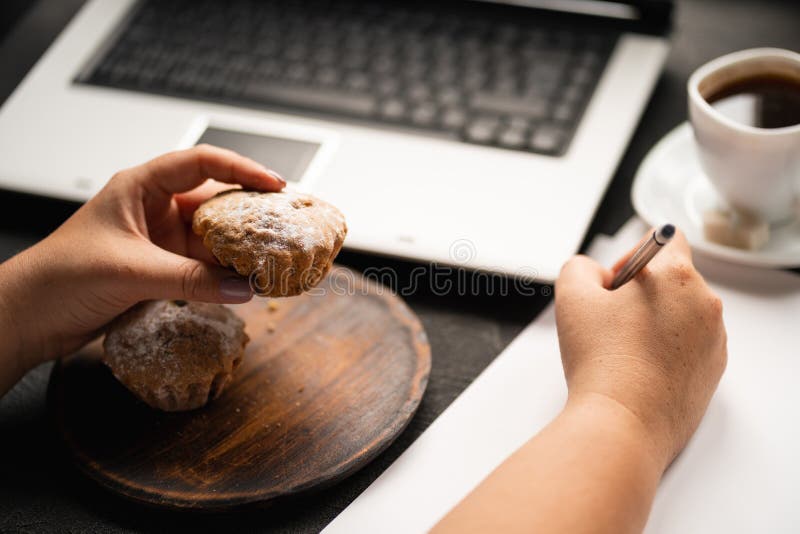 Donna che mangia muffin nel luogo di lavoro Spuntino non sano