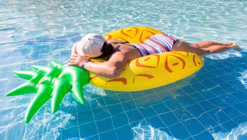 Donna che nuota in piscina con l'ananas gonfiabile fotografia stock libera da diritti Donna che nuota in piscina con l'ananas gonfiabile fotografia stock libera da diritti