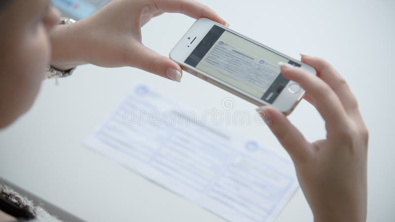 Donna che per mezzo del suo telefono per prendere immagine della ricevuta o della fattura Fatture di pagamento online da comodità