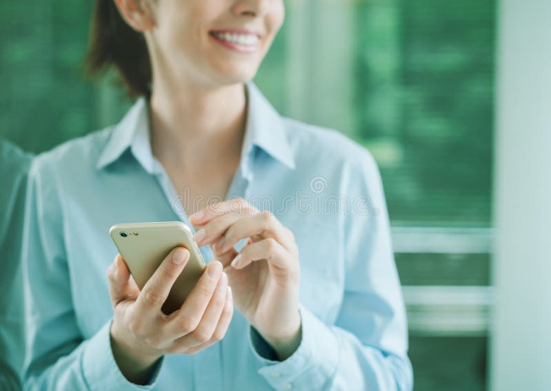 Donna che per mezzo di uno smartphone e appoggiandosi una finestra fotografia stock libera da diritti Donna che per mezzo di uno smartphone e appoggiandosi una finestra fotografia stock libera da diritti