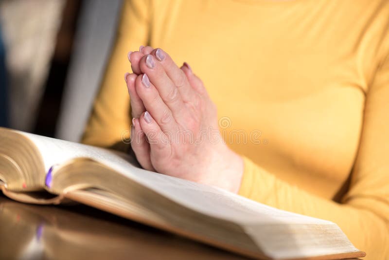 Donna che prega con le sue mani su bibbia fotografia stock Donna che prega con le sue mani su bibbia fotografia stock